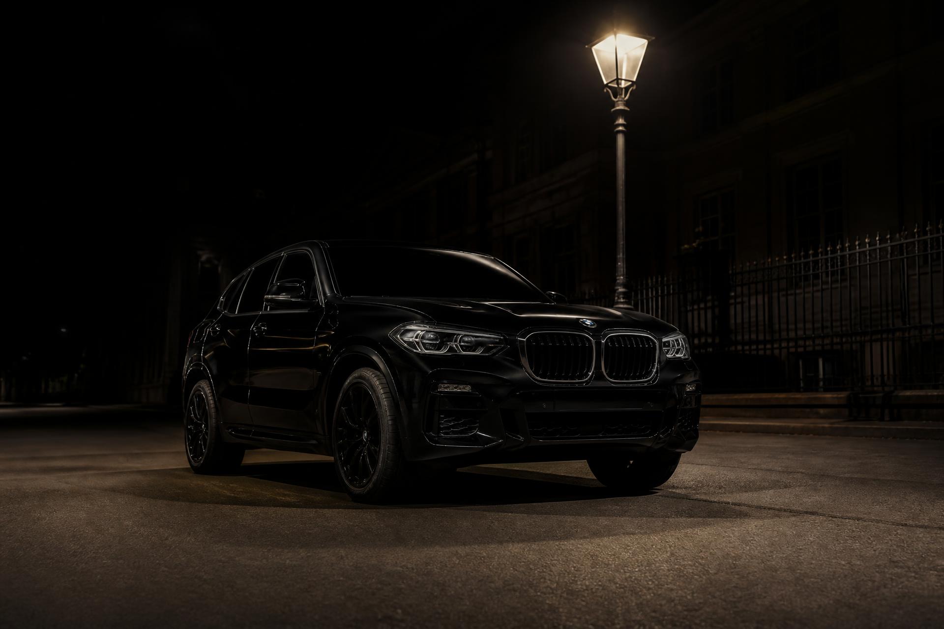 Shiny black BMW iX3 on a dark Hague street at night
